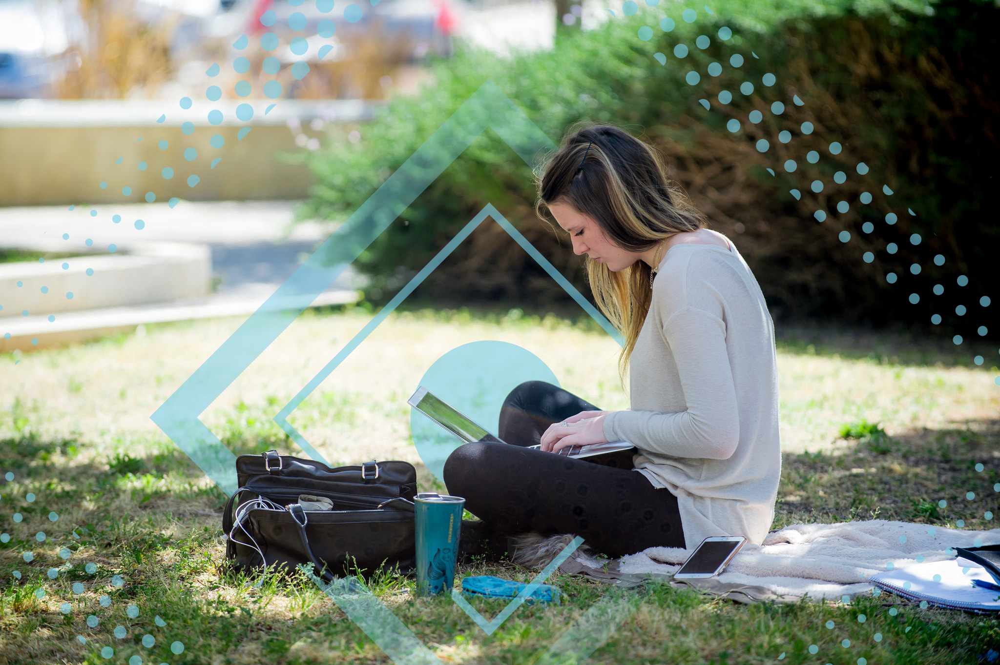 סטודנטית יושבת עם מחשב בדשא